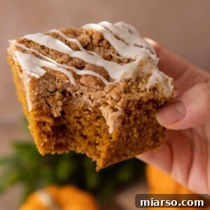 A perfect slice of pumpkin coffee cake with a generous crumb topping and vanilla glaze.