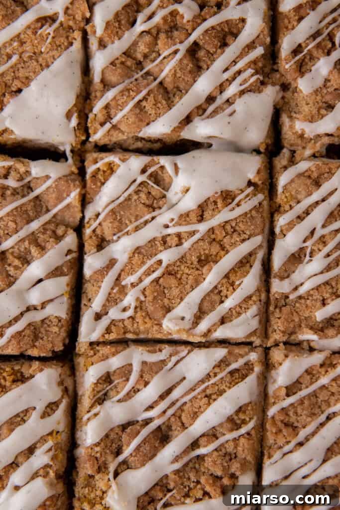 An overhead view of the pumpkin coffee cake recipe, freshly baked and glistening with a vanilla glaze, ready to be sliced.