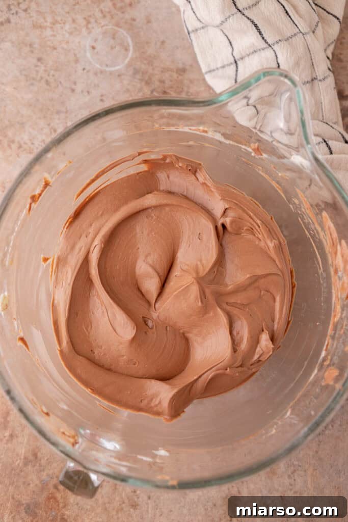 Whipped heavy cream with stiff peaks, ready to be folded into the chocolate cream cheese mixture.