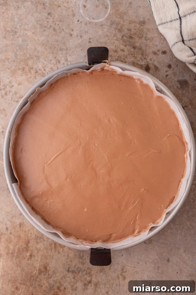 Smooth chocolate cheesecake filling spread evenly over the Oreo crust in a springform pan.