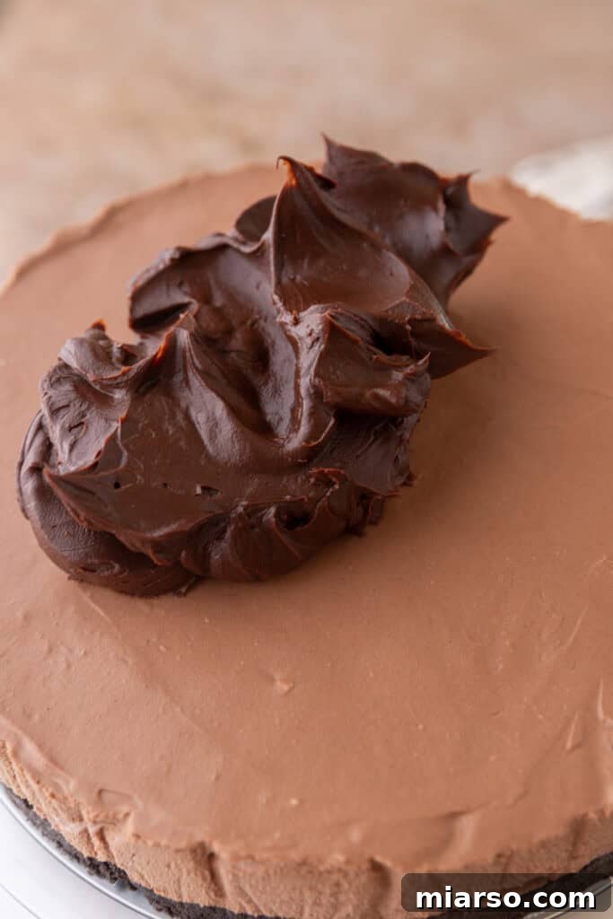 Thickened chocolate ganache being spread onto the top of the chilled chocolate cheesecake.
