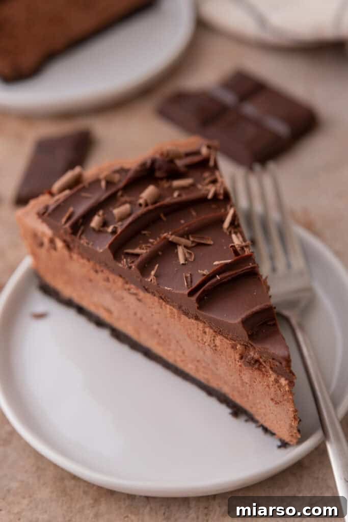A perfect slice of no-bake chocolate cheesecake on a white plate, highlighting its creamy filling and dark Oreo crust.
