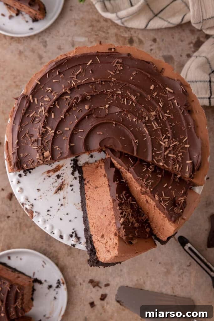 An overhead shot of the completed no-bake chocolate cheesecake with a slice missing, showing the thick ganache topping and a smooth texture.