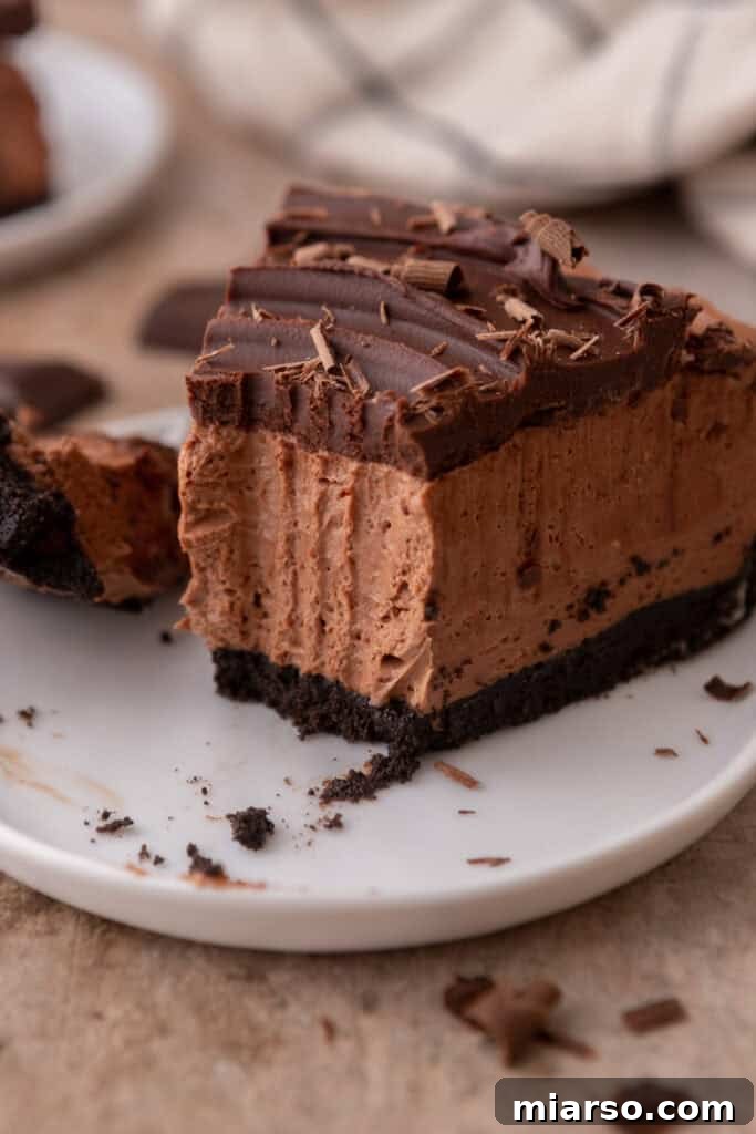 A close-up of a slice of no-bake chocolate cheesecake, showcasing its smooth texture and rich chocolate layers, ready to be enjoyed.