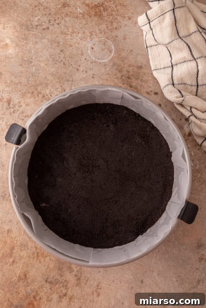 Melted butter combined with Oreo crumbs, forming a sticky mixture for the cheesecake crust.