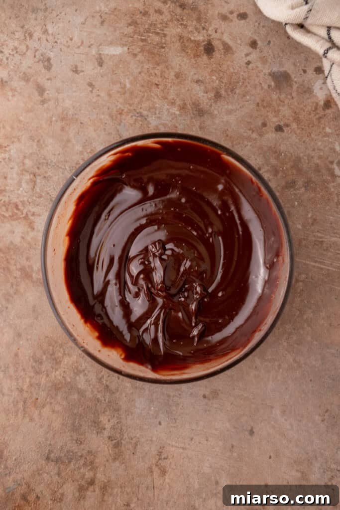 Smooth and glossy chocolate ganache after stirring, cooling slightly before use.