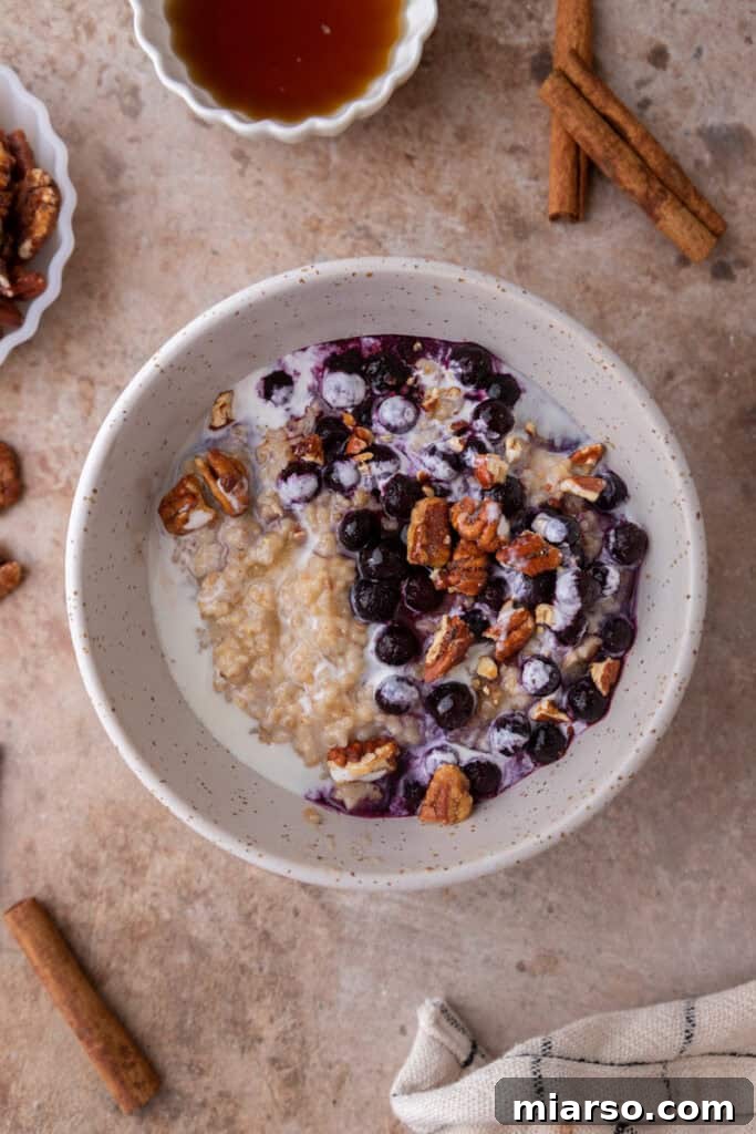 Overhead shot of a bowl of Instant Pot steel cut oats topped with fresh berries, nuts, and a drizzle of maple syrup.