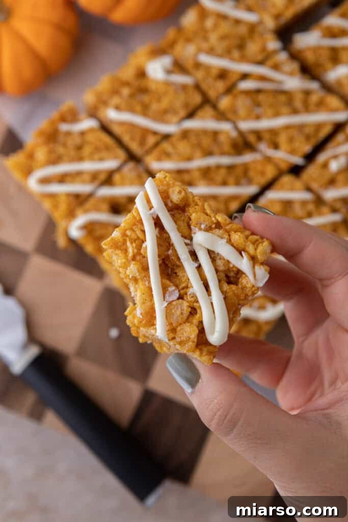 Overhead shot of several pumpkin rice krispie treats, some with white chocolate drizzle, ready to be enjoyed.