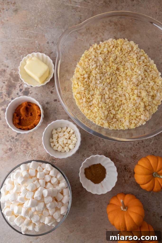Essential ingredients laid out for pumpkin rice krispie treats including marshmallows, butter, pumpkin puree, and spices.