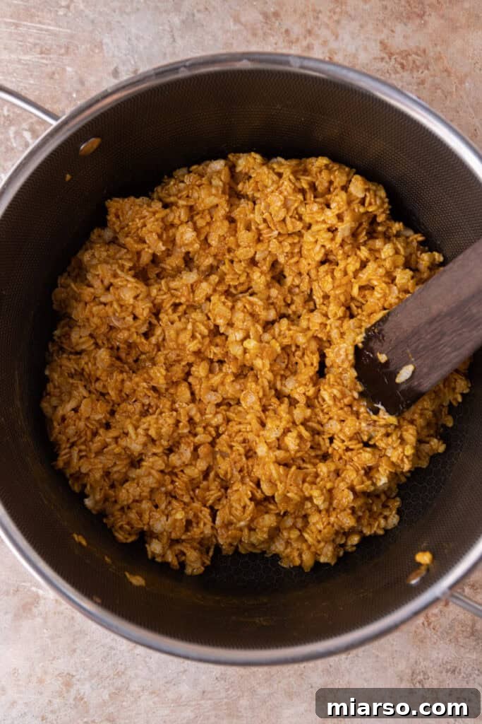 Rice Krispies cereal being folded into the pumpkin-marshmallow mixture.