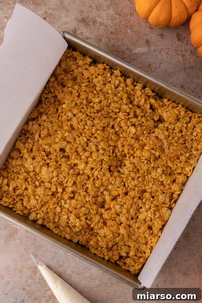 The pumpkin Rice Krispie treat mixture pressed firmly into a square pan.