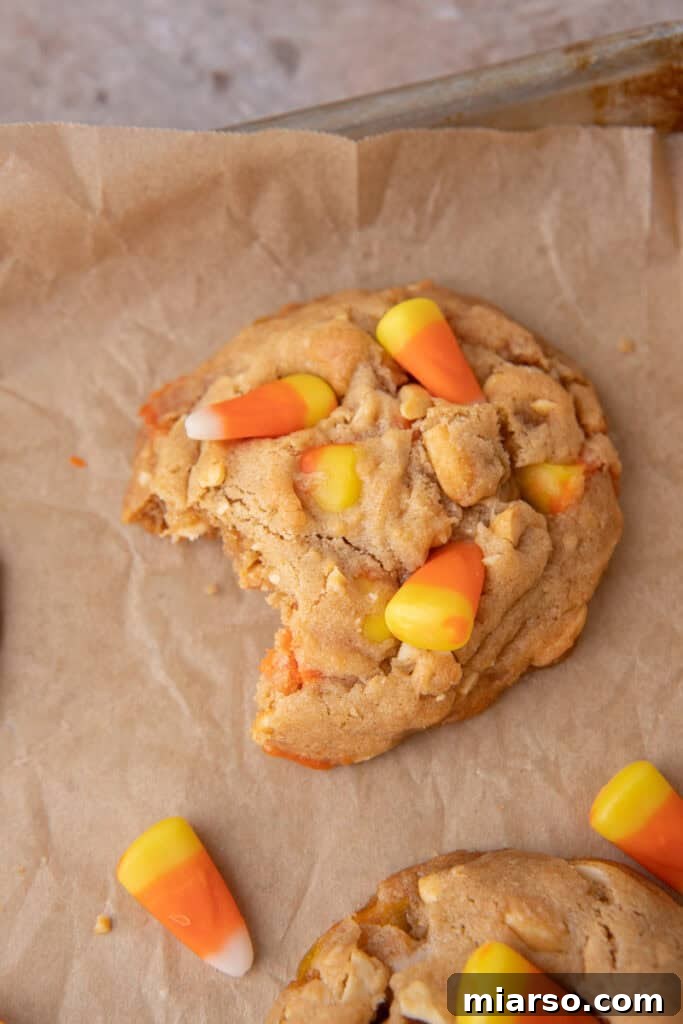 An overhead shot of a candy corn cookie with a bite taken out, emphasizing its appealing texture and fillings.