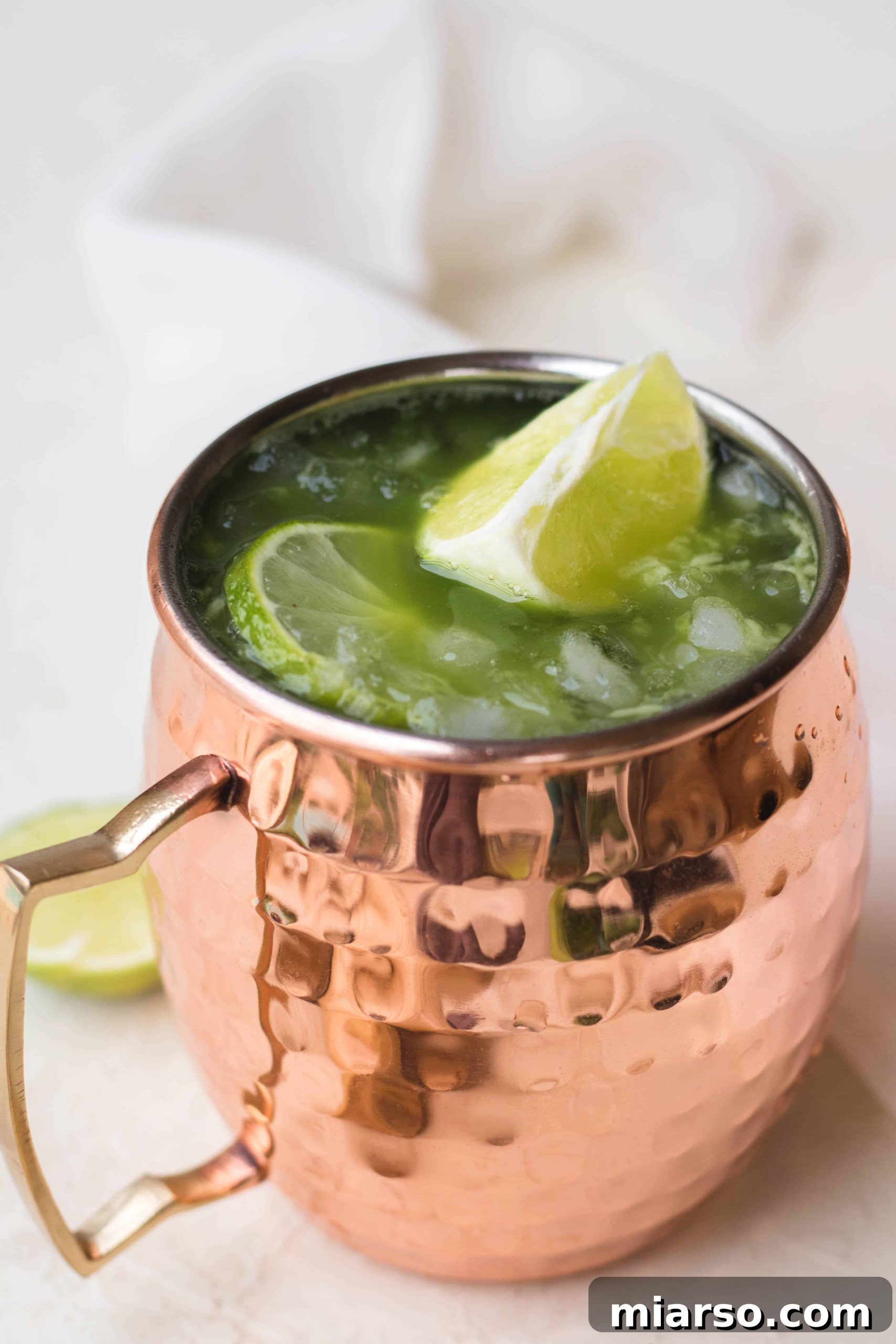 Close-up of a Virgin Matcha Moscow Mule with fresh lime slices and grated ginger