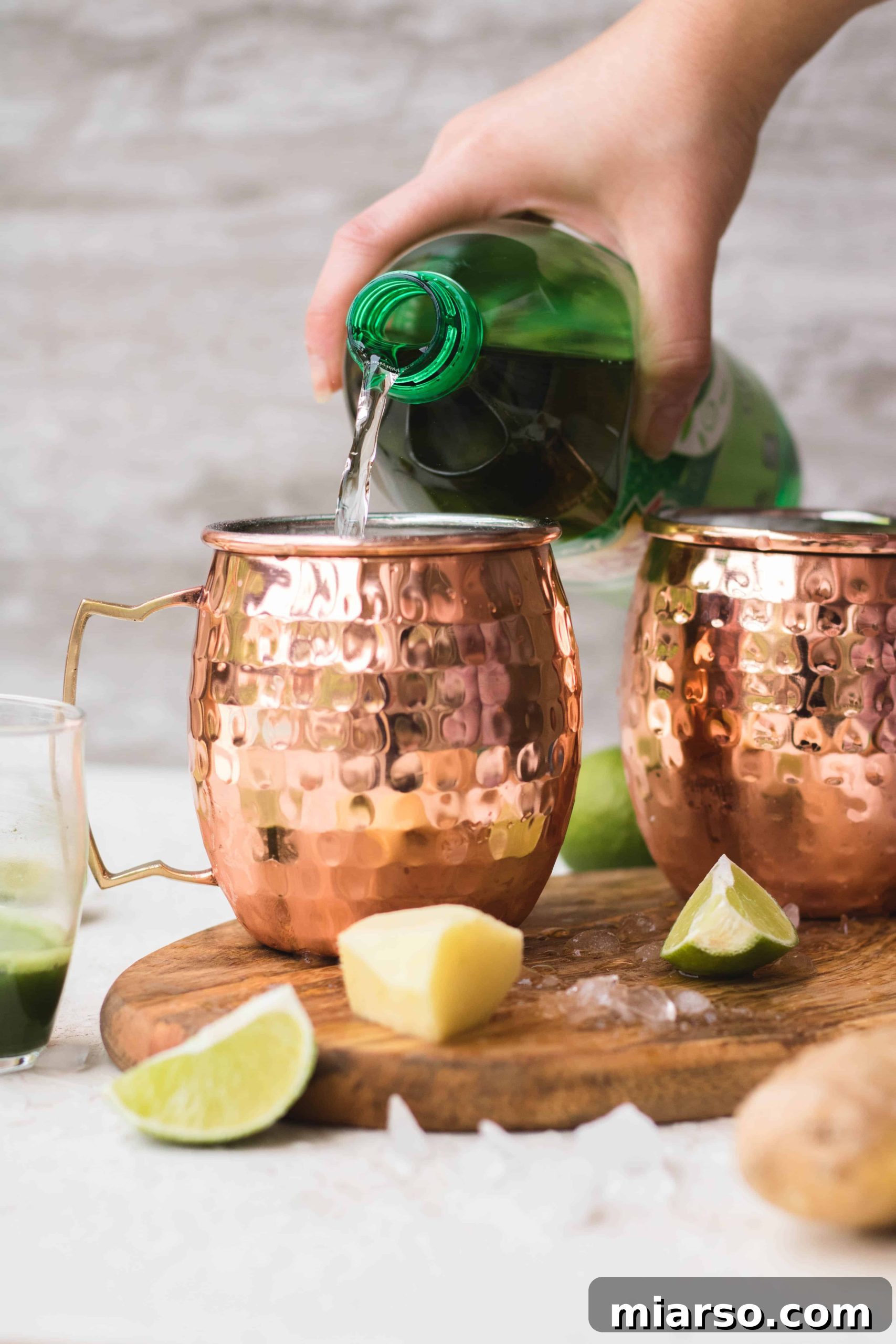 Pouring ginger ale into copper Moscow Mule mugs