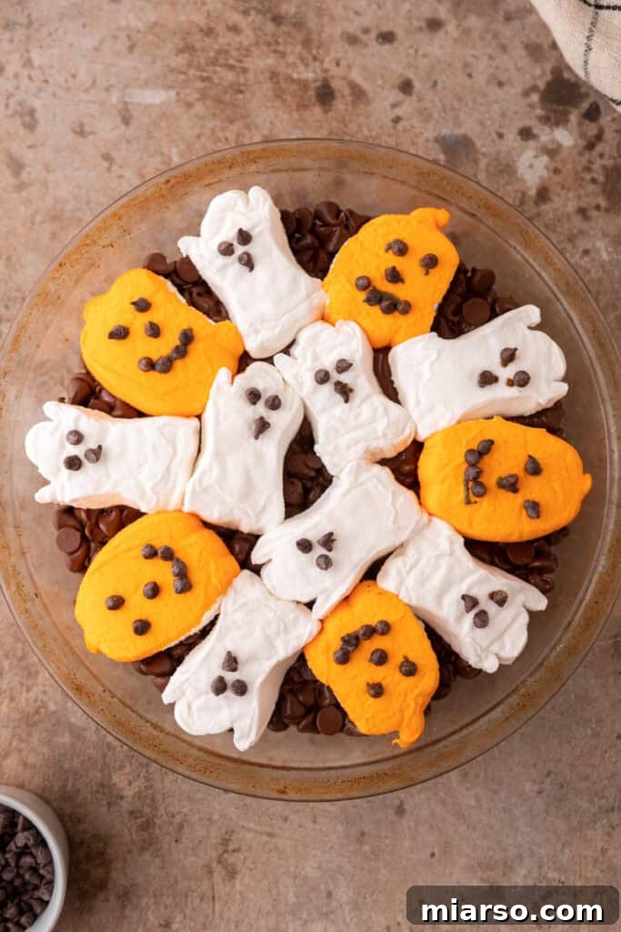 Bewitching Halloween S'mores Dip 6 chocolate chips in a baking dish with marshmallows on top