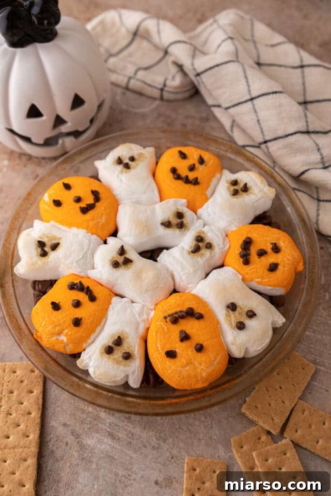 Bewitching Halloween S'mores Dip 9 chocolate chips in a baking dish with marshmallows on top fully baked