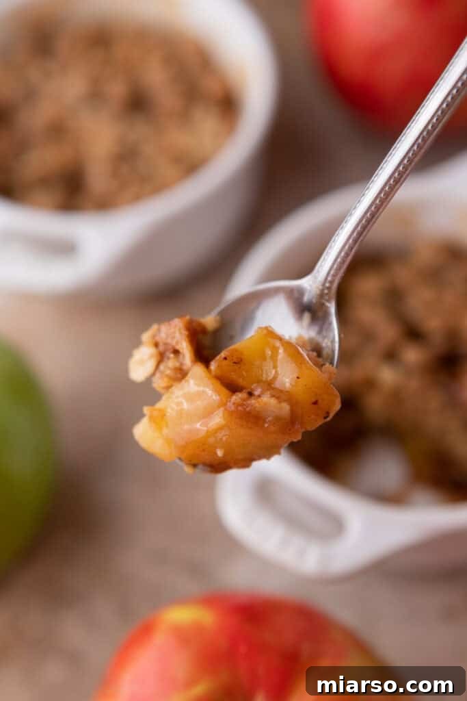 A spoonful of Microwave Apple Crisp for One, showing the textural contrast between soft apples and crumbly topping.