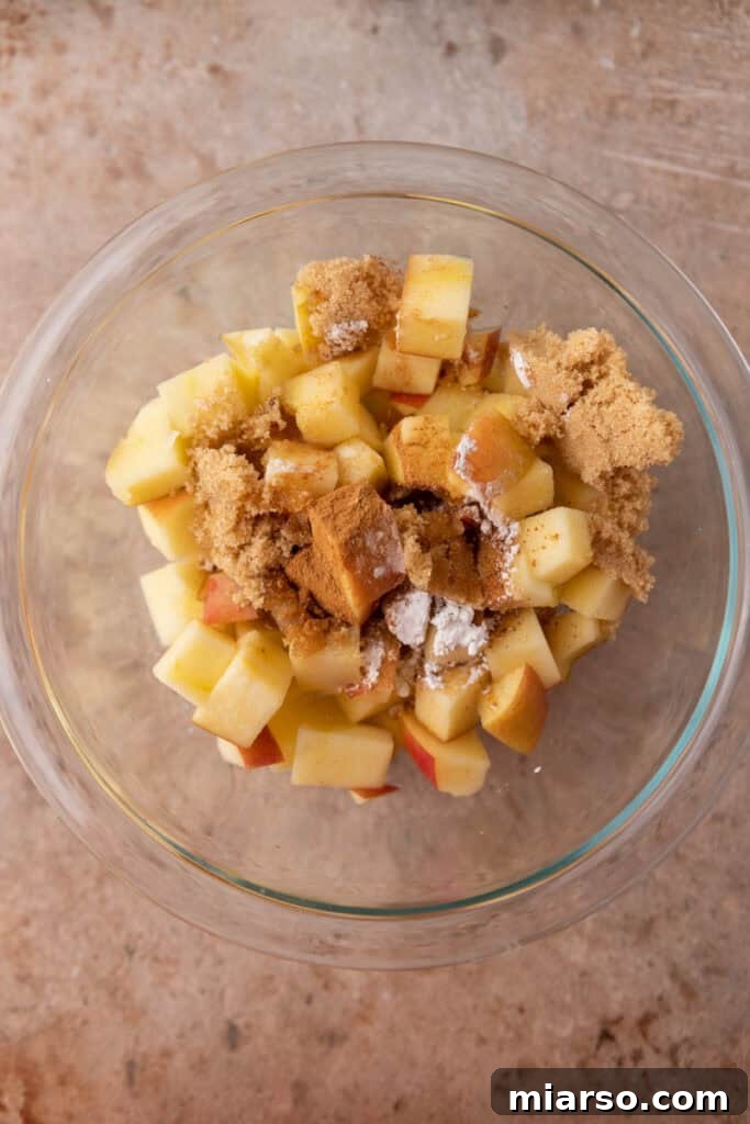 Unmixed diced apples with spices in a bowl, ready for the microwave.