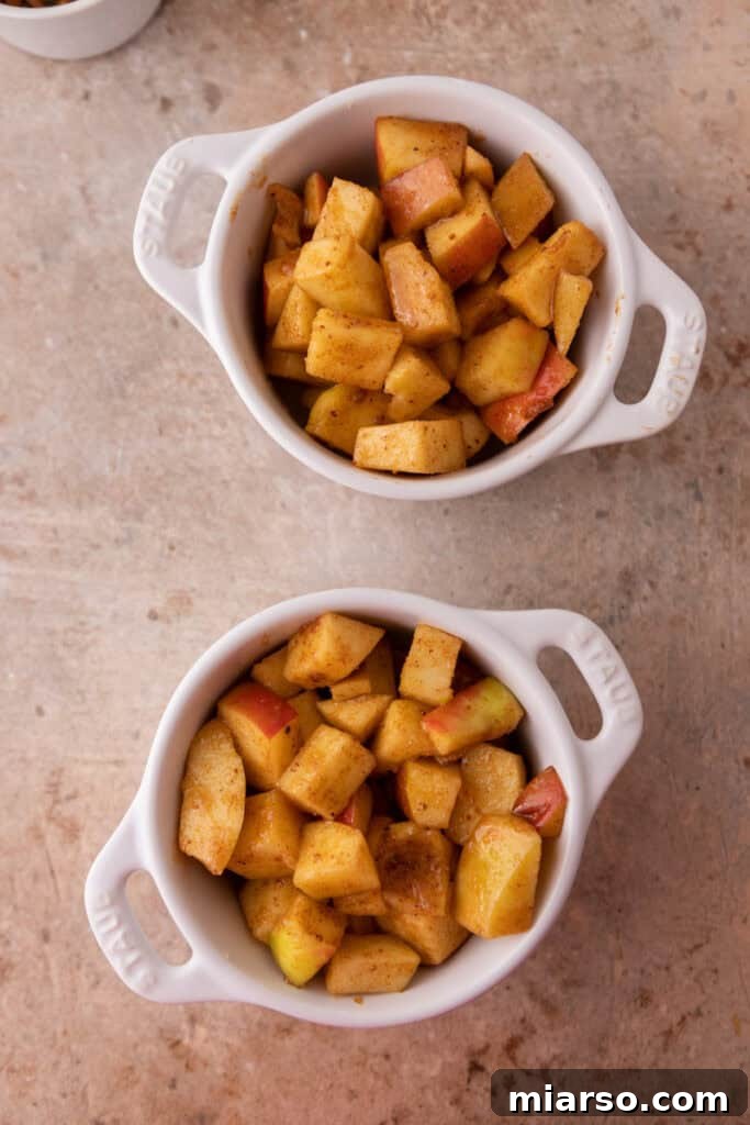 Prepared apple filling divided into two smaller ramekins for single servings.