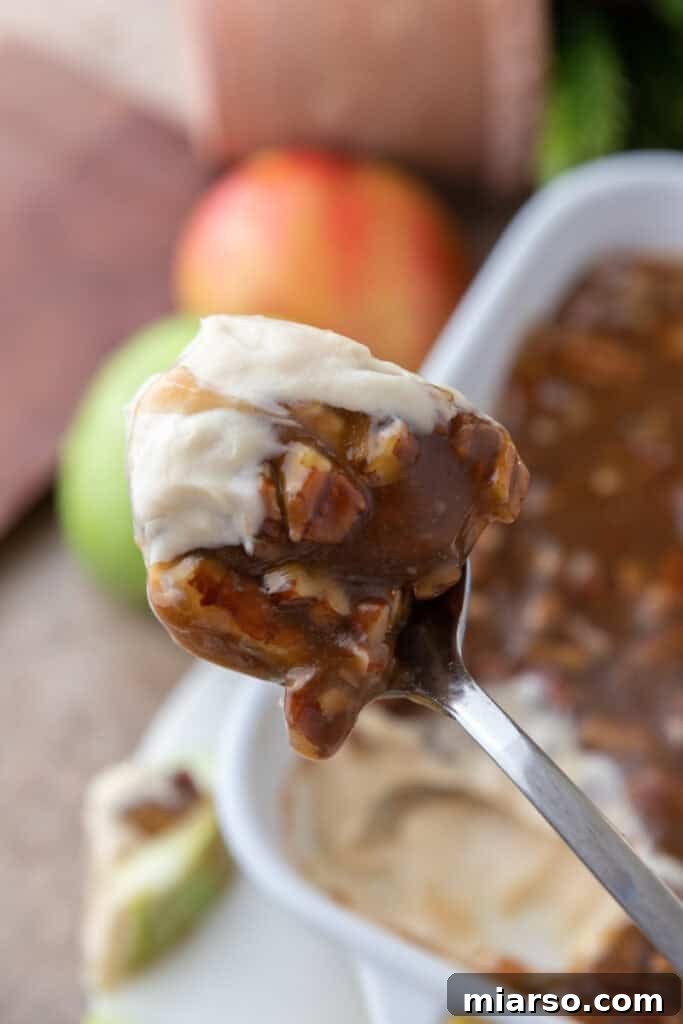 Irresistible Pecan Pie Dip 2 Scooping a spoonful of rich Pecan Pie Dip from a serving bowl, showcasing its creamy texture and chunky pecan topping.