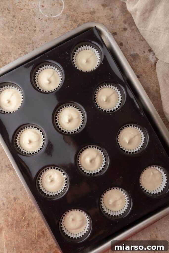 Nilla Wafer Mini Cheesecake Perfection 8 Raw cheesecake batter spooned over Nilla wafers in a muffin tin, ready for baking.