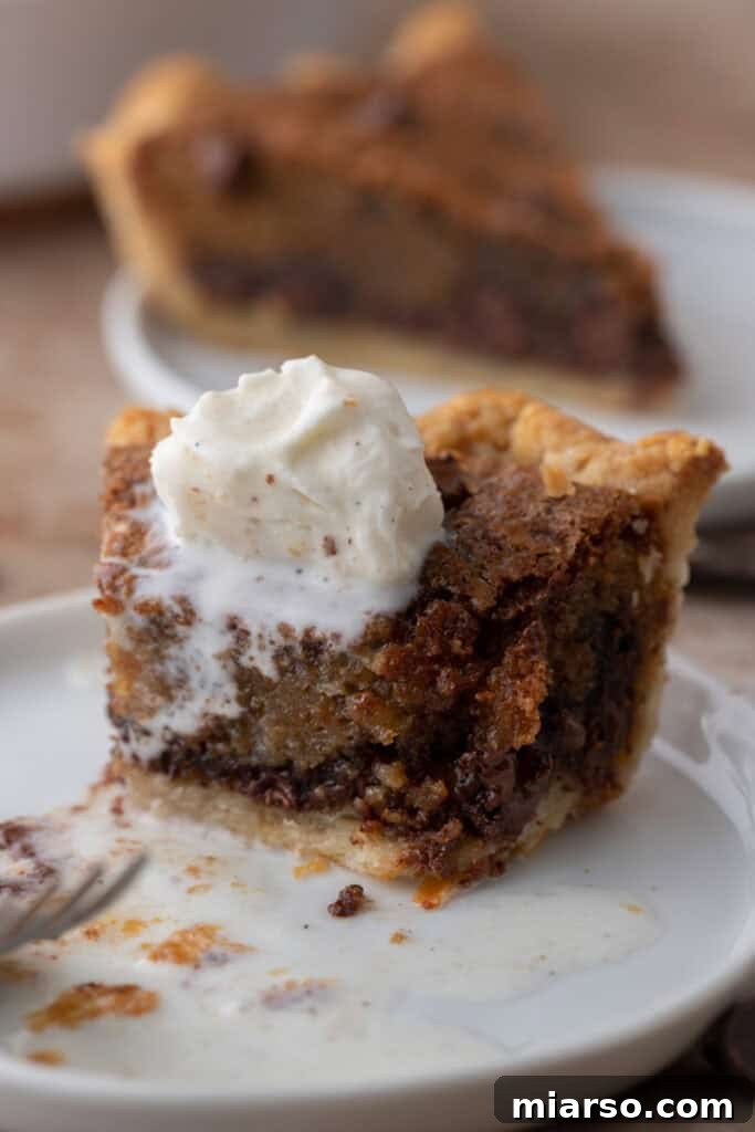 a slice of the chocolate chip cookie pie recipe topped with a scoop of vanilla ice cream