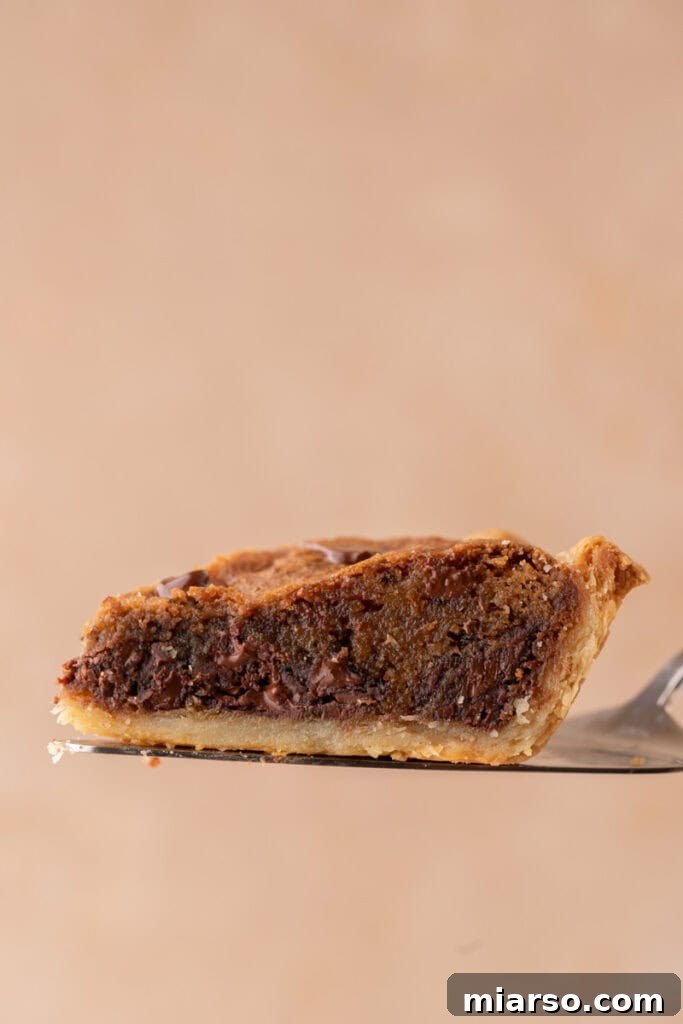 a perfectly baked slice of chocolate chip cookie pie, golden brown and glistening with melted chocolate