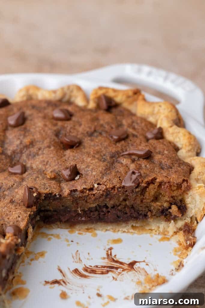 Side shot of chocolate chip cookie pie, showing its thick, gooey interior and flaky crust