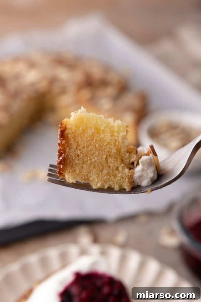A fork holding a piece of almond cake, showcasing its delicate texture