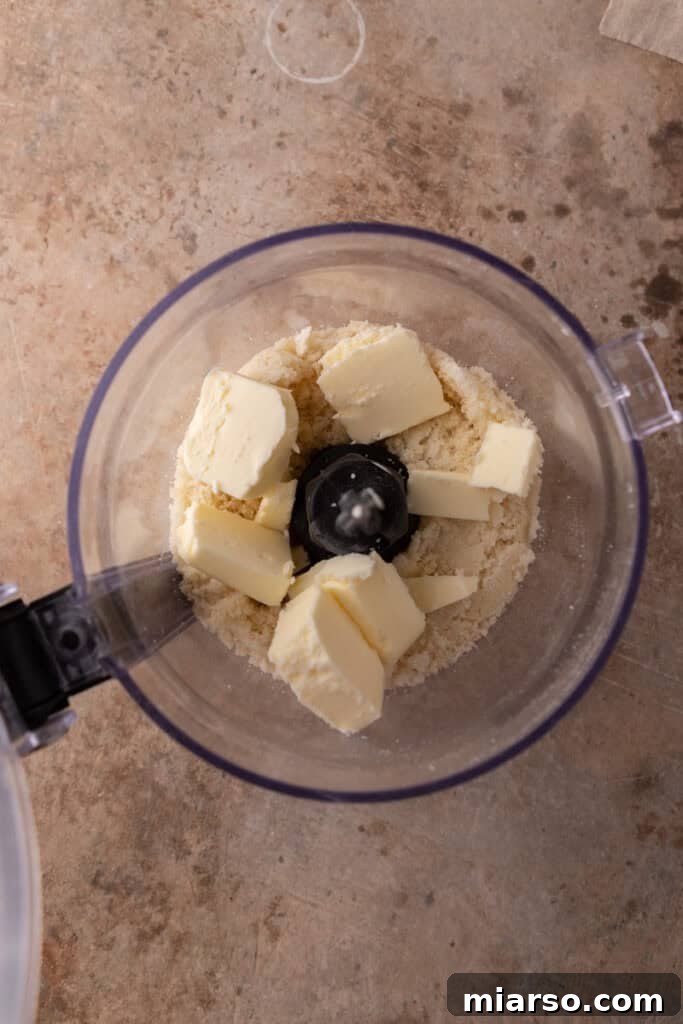 Almond paste and sugar being processed into fine crumbs