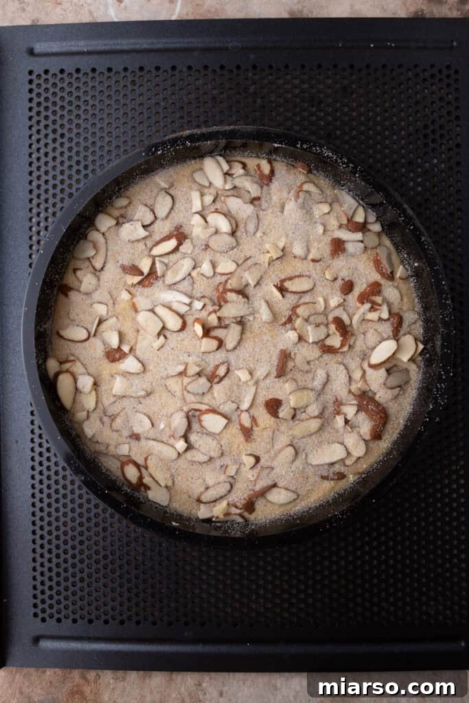 Unbaked almond cake batter spread evenly in the prepared pan