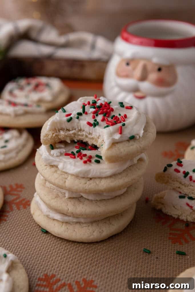 Soft and Fluffy Sour Cream Sugar Cookies 13 Beautifully decorated Christmas sour cream sugar cookies, frosted with smooth white icing and adorned with festive red and green sprinkles, ready for holiday celebrations.