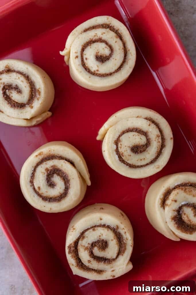 Perfect Small Batch Cinnamon Rolls 11 Six unbaked small-batch cinnamon rolls arranged in a red baking pan before rising.