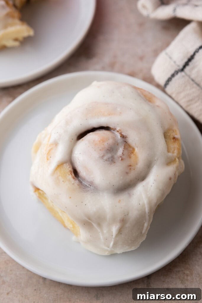 Perfect Small Batch Cinnamon Rolls 13 Single frosted small batch cinnamon roll on a white plate with creamy vanilla bean icing.