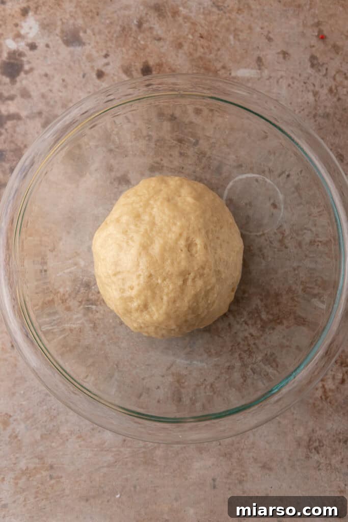 Perfect Small Batch Cinnamon Rolls 6 Smooth, soft ball of cinnamon roll dough resting in a glass bowl after kneading.