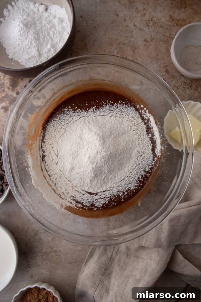 Dry ingredients (flour, baking soda, baking powder, salt) sifted into a bowl, awaiting combination with wet ingredients.
