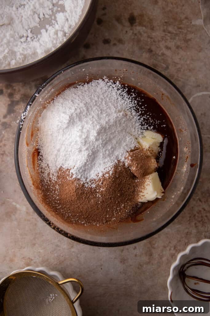 Semi-sweet chocolate chips in a bowl, with hot heavy cream poured over them, steeping.