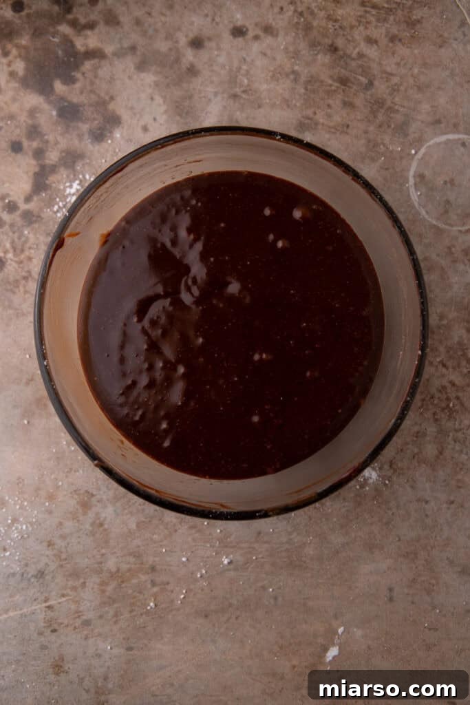 Rich chocolate ganache mixture, after stirring, with butter and powdered sugar added, before final beating.
