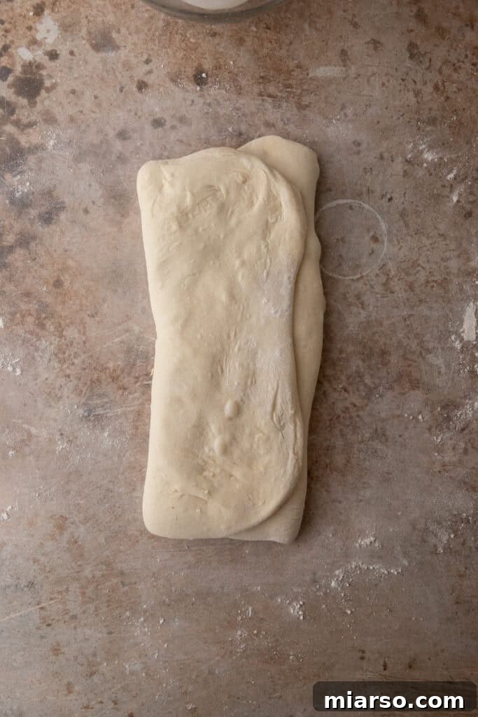 stretched out dough folded on a floured surface