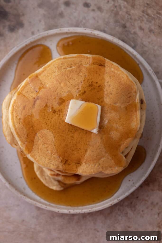 Overhead shot of sourdough discard pancakes with fresh berries and maple syrup