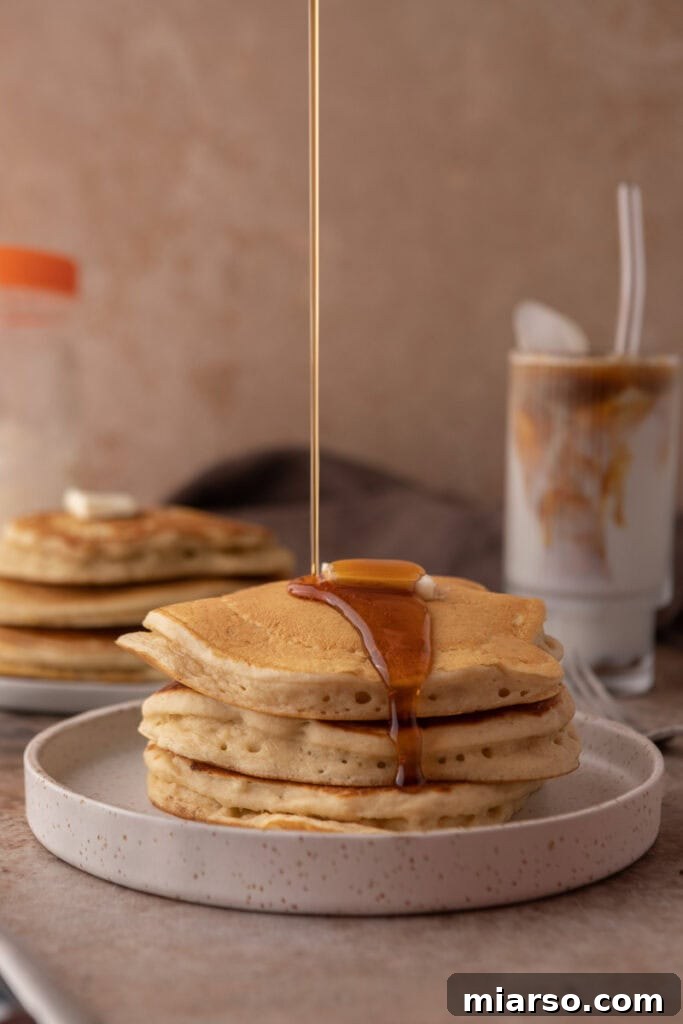 Side view of fluffy sourdough discard pancakes with syrup and fruit