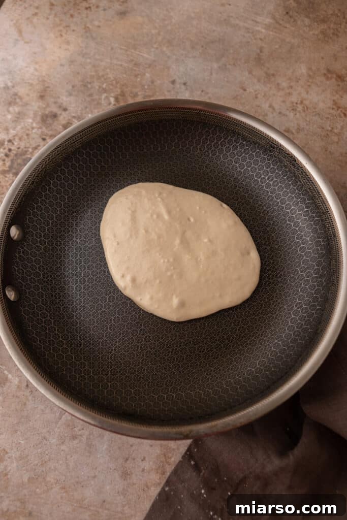 Sourdough pancake batter cooking in a hot pan