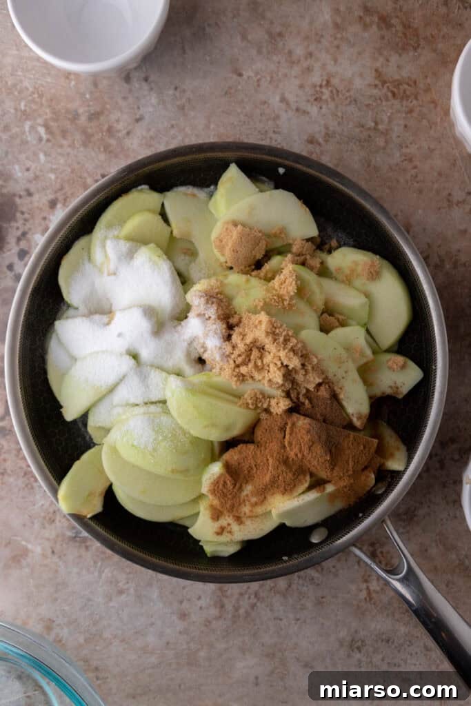 Effortless Apple Filling for Delicious Desserts 7 Uncooked apple pieces, sugars, and spices in a pot, ready to be stirred.
