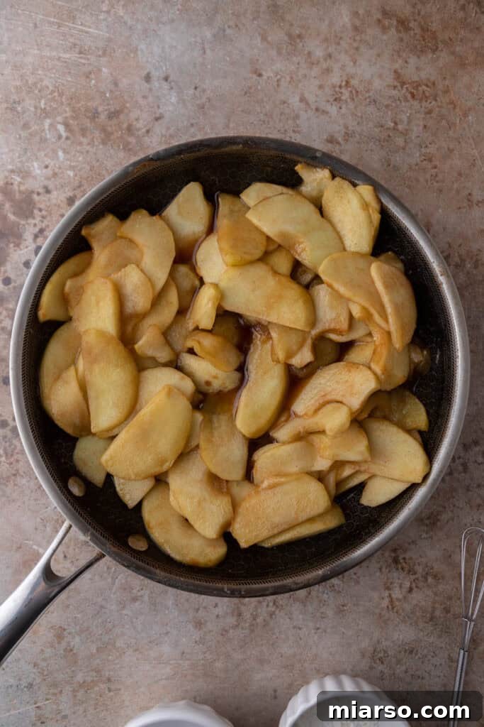 Effortless Apple Filling for Delicious Desserts 8 Apples cooking in a pot with butter, sugar, and spices, starting to soften.