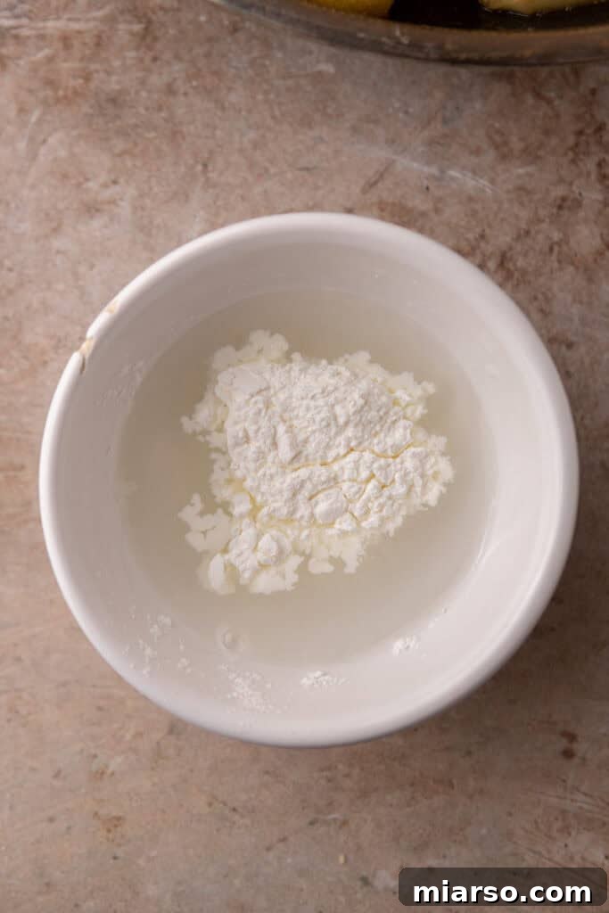 Effortless Apple Filling for Delicious Desserts 9 A small bowl holding a cornstarch slurry, a mixture of cornstarch and water.