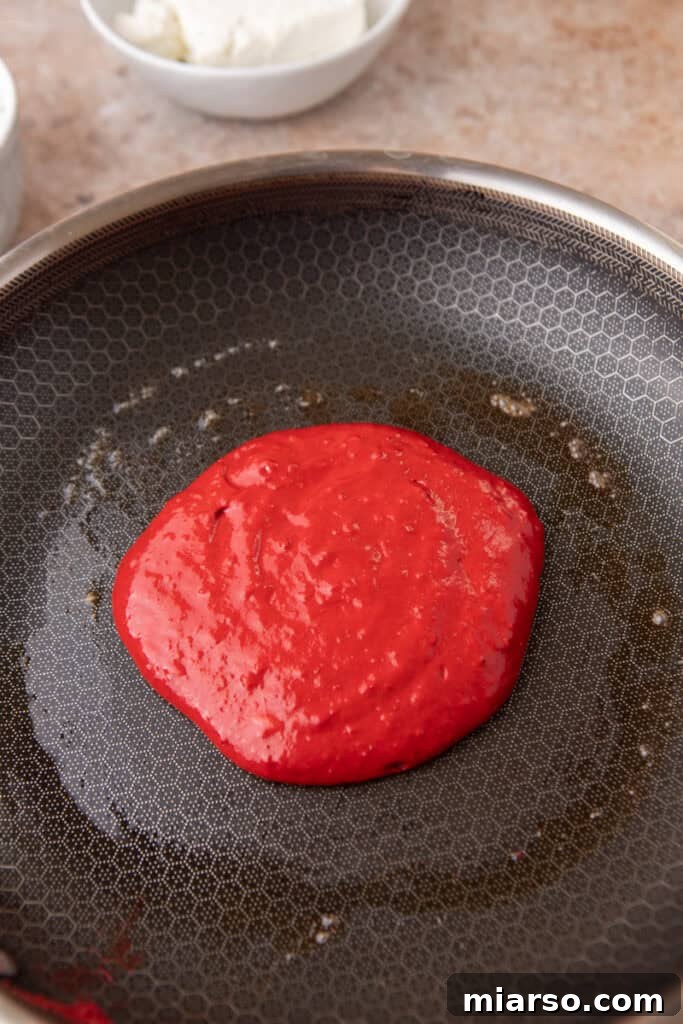 Indulgent Red Velvet Pancakes 8 A Red Velvet Pancake cooking on a griddle, showing bubbles forming on the surface, indicating it's ready to flip.