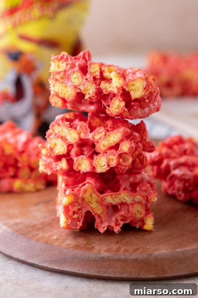 Stacked Hot Cheetos Marshmallow Crispy Treats on a serving plate, showcasing their vibrant red color and gooey texture.