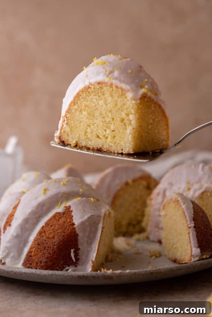A perfectly sliced piece of moist lemon bundt cake, showcasing its tender crumb and glossy lemon glaze.