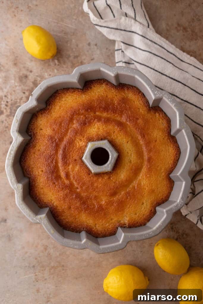 Warm lemon syrup being brushed over the baked bundt cake