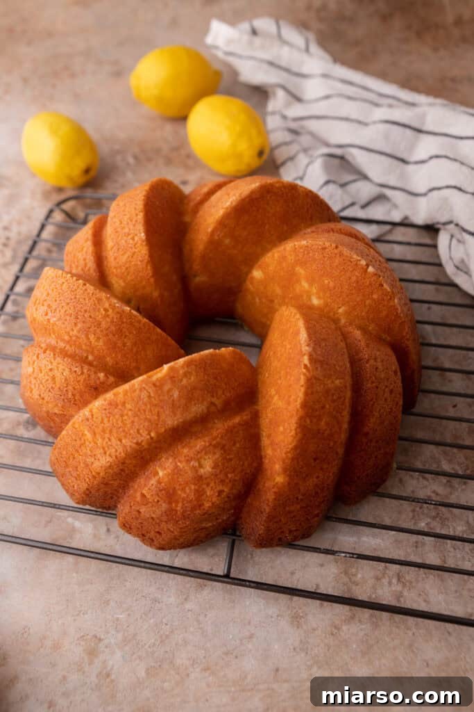 The lemon bundt cake cooling on a wire rack after syrup application